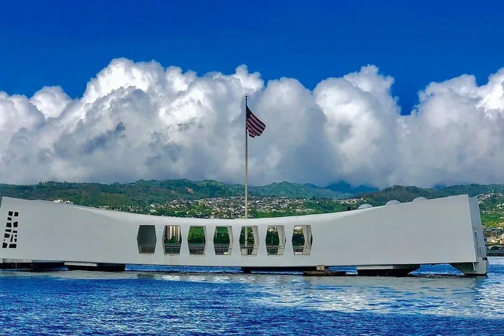 Il memoriale bianco della USS Arizona e la sua bandiera sotto alte nuvole bianche