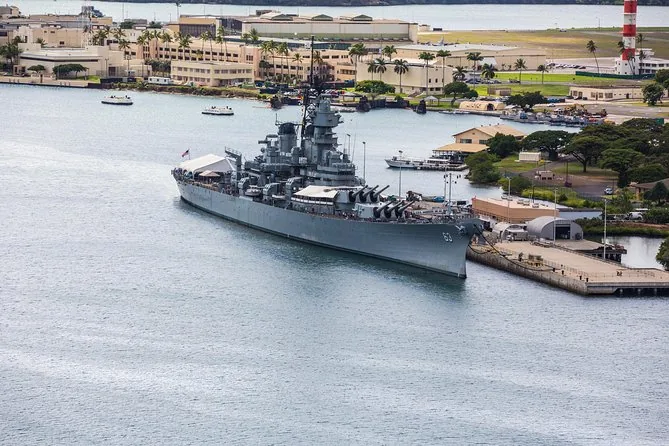 The Battleship Missouri at her pier with Ford Island buildings and a red and white control tower behind