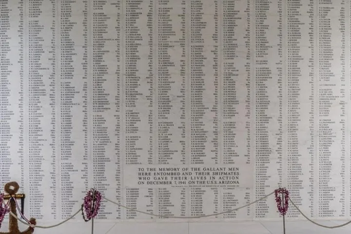 The marble shrine room wall with columns of engraved names and leis below