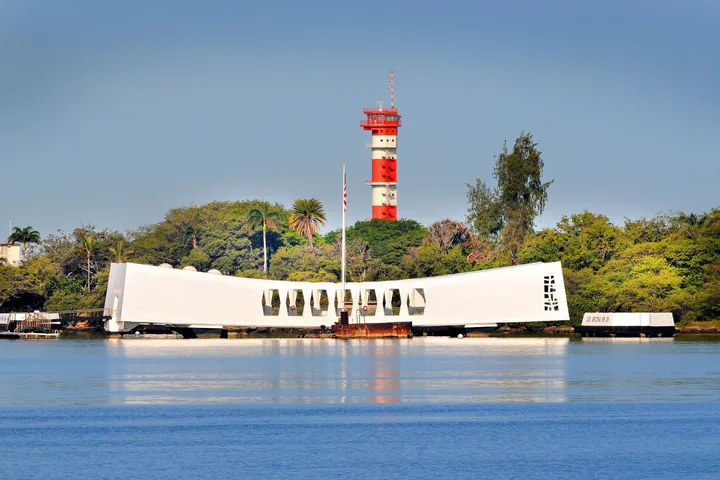 Il memoriale bianco della USS Arizona con la torre di controllo rossa e bianca di Ford Island alle spalle