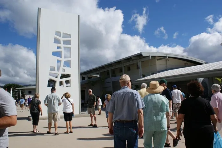 Visitors walking into the Pearl Harbor Visitor Center past a tall white sculpture