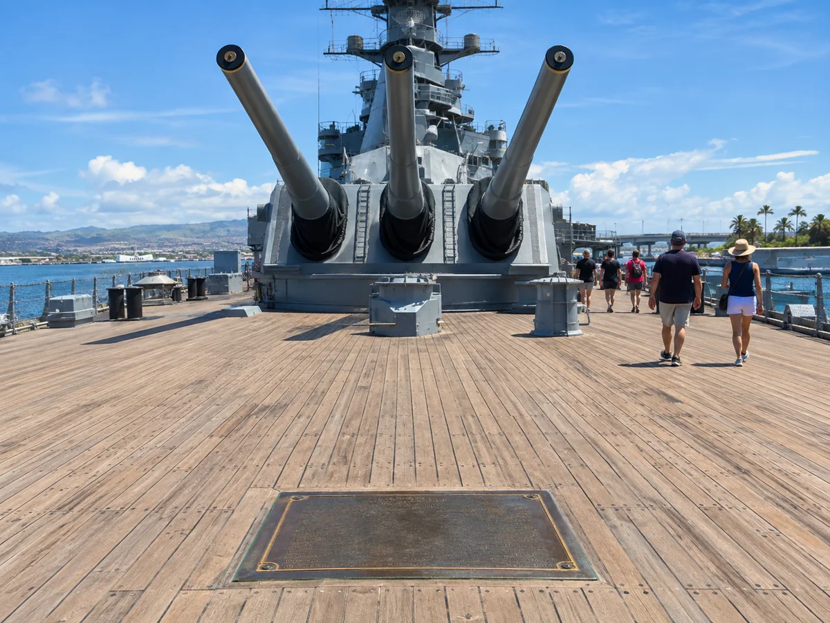 Das Hauptdeck aus Teakholz des Schlachtschiffs Missouri mit einer Bronzetafel und den vorderen 16-Zoll-Geschützen